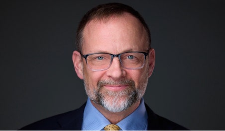 A person wearing glasses and a suit AI-generated content may be incorrect.