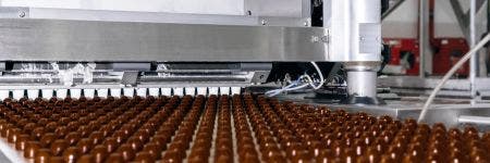 Filas de adición de cobertura para chocolates fabricados a máquina en una cinta transportadora (fábrica de chocolate)