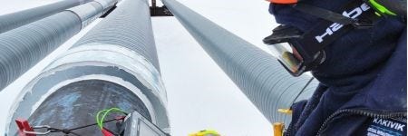 Kakivik Asset Management inspector inspecting a pipeline using Evident ultrasonic inspection technology in snow-covered Alaskan oilfield